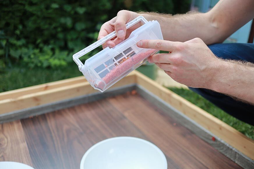 Ein Finger deutet auf die Staubrückhalteklappe des Ecovacs Deebot T10 